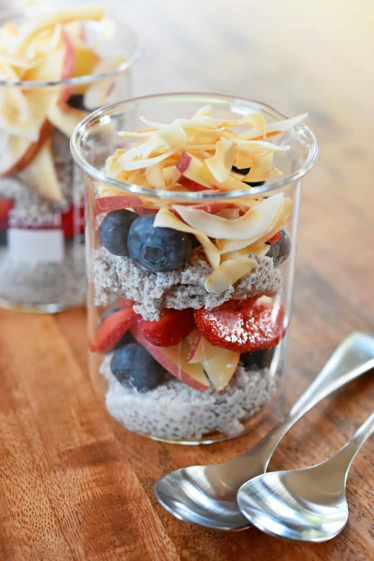 Two jars of coconut chia pudding topped with fresh fruit and toasted coconut.
