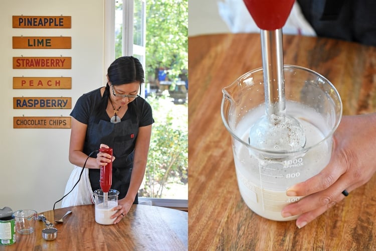 A woman is using an immersion blender to mix the ingredients for the coconut chia pudding.