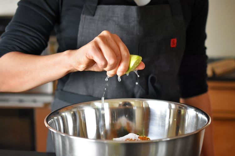 Squeezing lime juice into a mixing bowl filled with the raw ingredients for healthy Curry Turkey Bites 