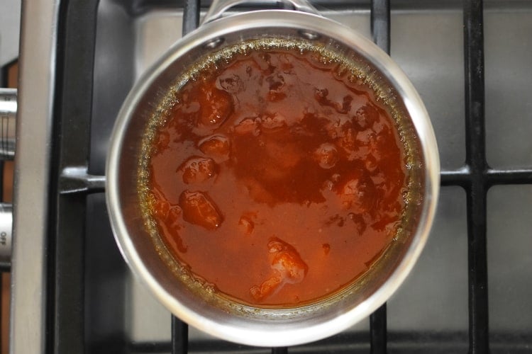 An overhead shot of a small saucepan filled with simmering Apricot-Ginger Sauce for Paleo Curry Turkey Bites