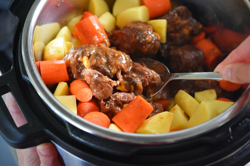 Stirring the Instant Pot Beef Stew to distribute the root vegetables