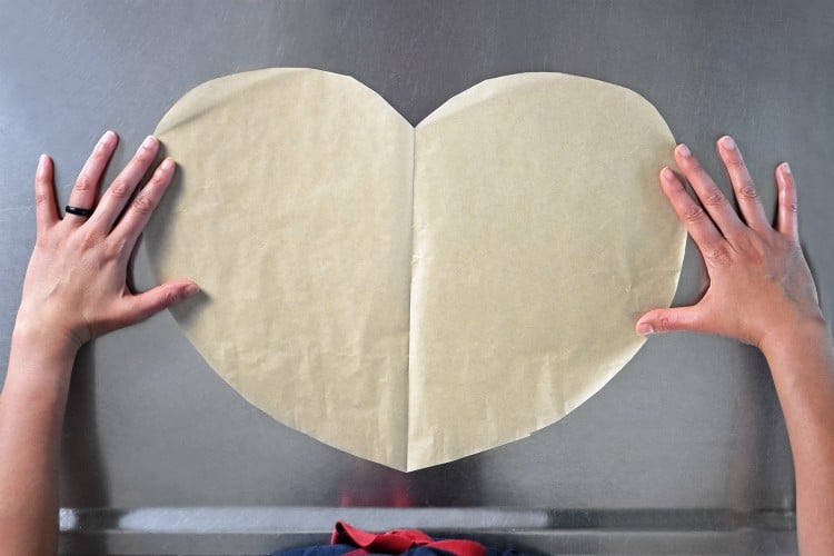 An overhead shot of a piece of parchment paper cut in the shape of a heart to make Lemon Garlic Chicken Parchment Packets 