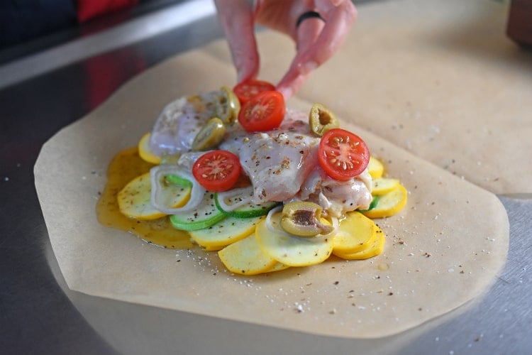 Adding halved cherry tomatoes to the Lemon Garlic Chicken Parchment Packets.