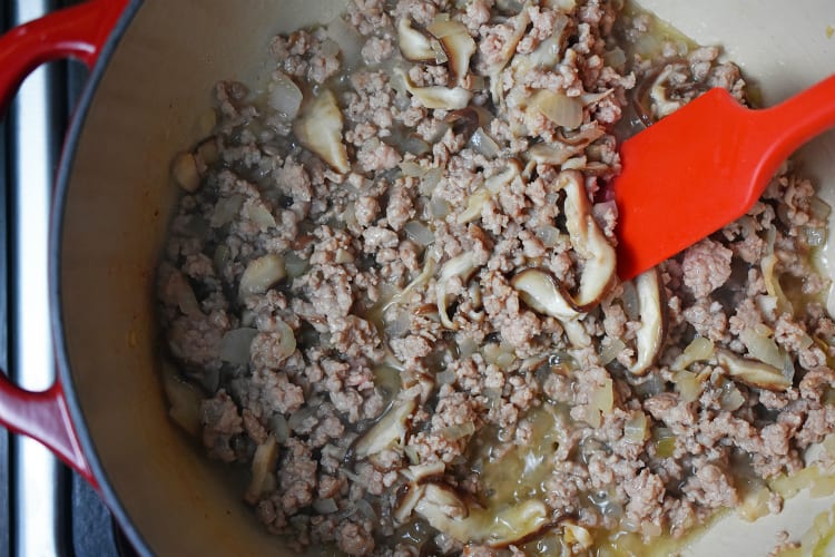 An overhead shot of the cooked ground pork, mushrooms, and diced onions in the pot.