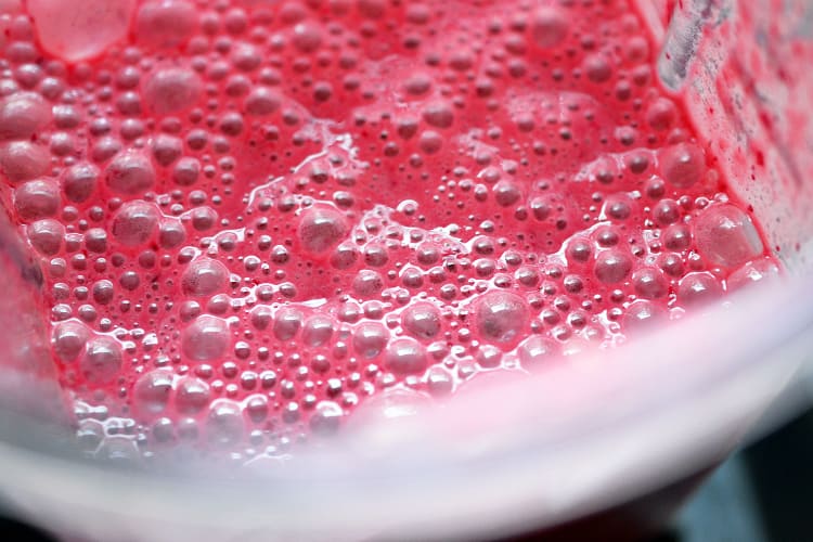 A close up of the bubbly, pink, cherry marinade in the blender.