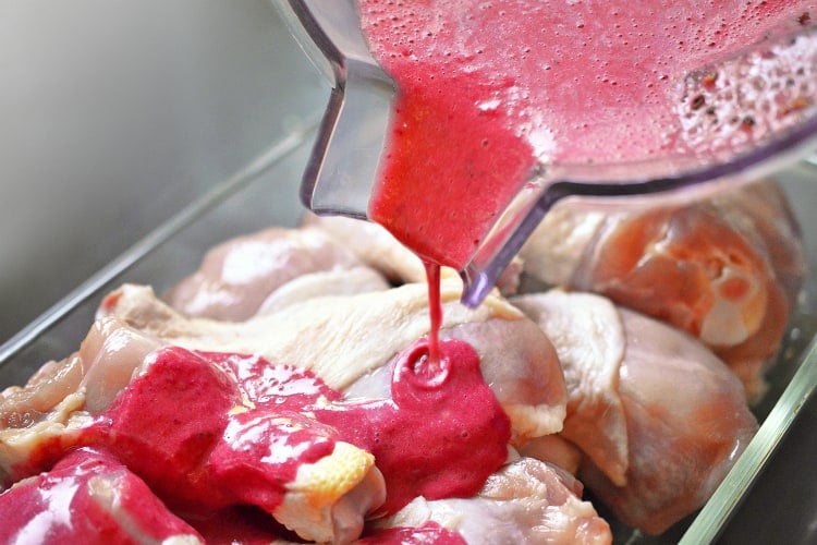 Pouring the pink cherry marinade in the bowl of chicken drumsticks.