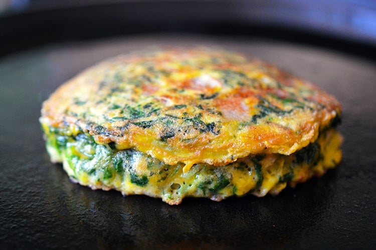 An Egg Foo Young savory Chinese pancake is finished frying on a cast iron skillet.