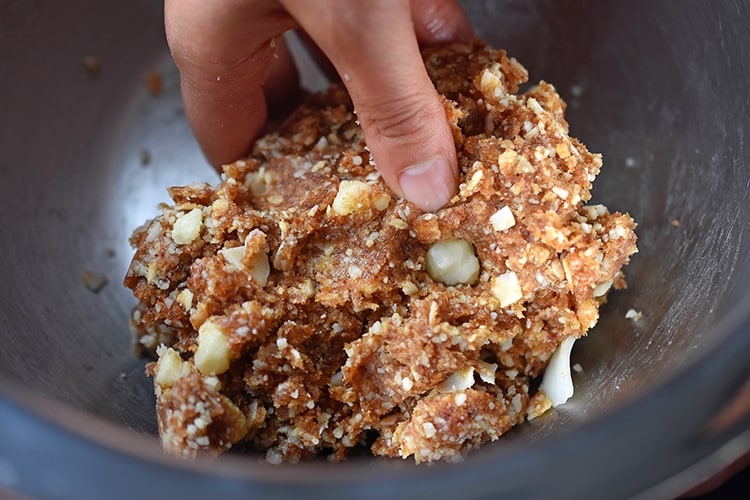 Someone mixing the ingredients for liar balls, healthy no-cook energy balls, in a metal bowl.