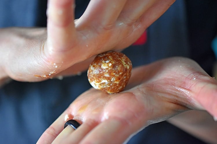 Someone rolling a paleo energy ball in between their hands.