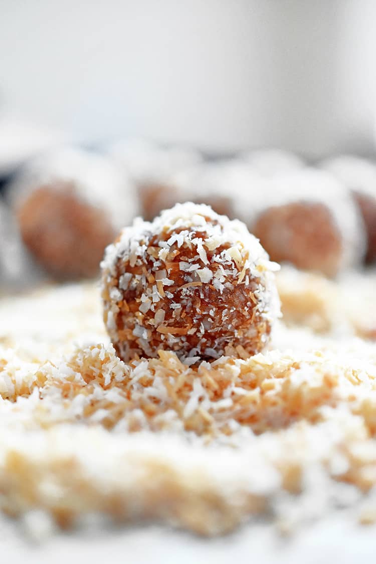 A Liar Ball, a paleo no-cook healthy energy ball, in a pile of toasted shredded coconut.