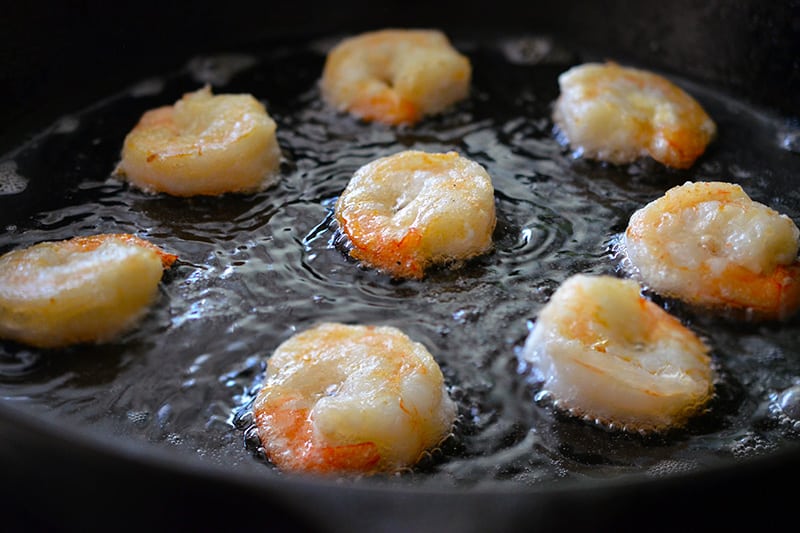 Paleo Walnut Shrimp frying in a cast iron skillet until golden on the outside.