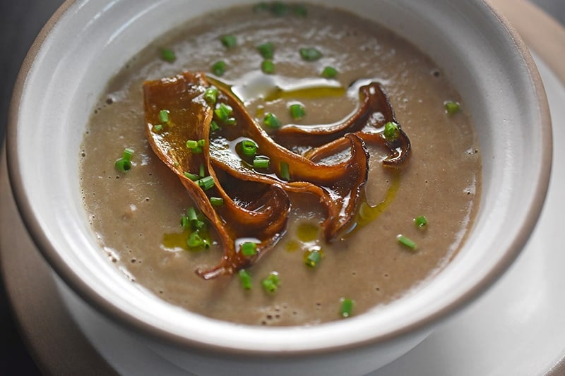 A bowl of Instant Pot cream of mushroom soup topped with mushroom chips.