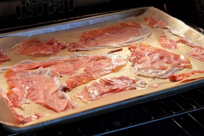 A tray of sliced prosciuttos going into the oven to make porkitos.