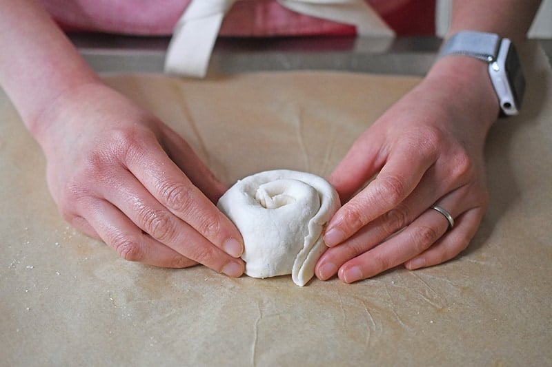 Someone holding a Paleo Scallion Pancake dough that has been formed to look like a cinnamon roll.