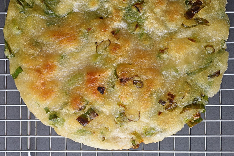 An overhead shot of a crispy Paleo and gluten-free Scallion Pancakes on a wire cooling rack.