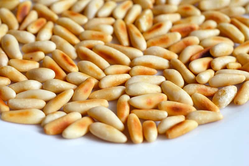 Toasted pine nuts on a plate for a swiss chard salad.