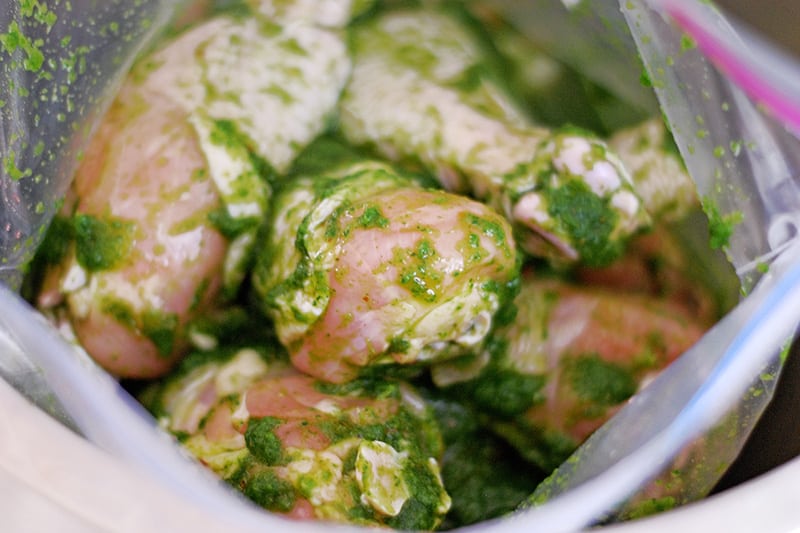 An overhead shot of the green gluten-free chicken marinade distributed evenly over the raw chicken in the ziplock bag. 