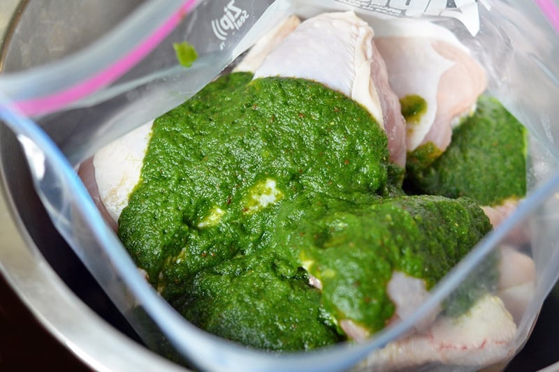 An overhead shot of the green paleo marinade on the raw chicken in a Ziplock bag to make Green Chicken.