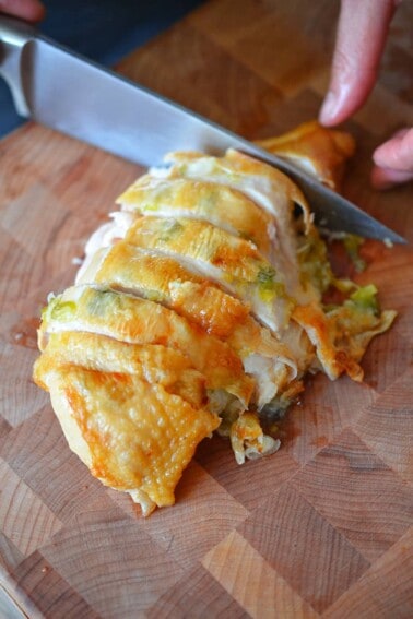 An overhead shot of Ginger-Scallion Chicken being sliced on a wooden cutting board.
