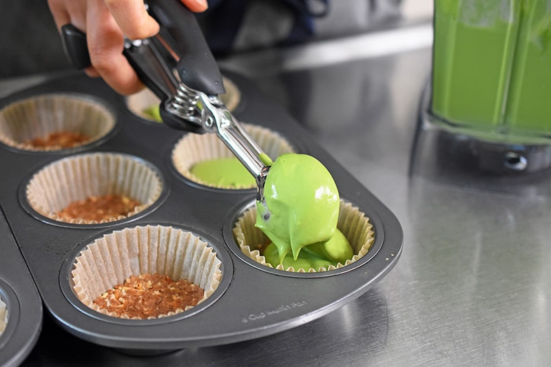 Scooping the No-Bake Matcha Cheesecake filling into the cupcake holders.