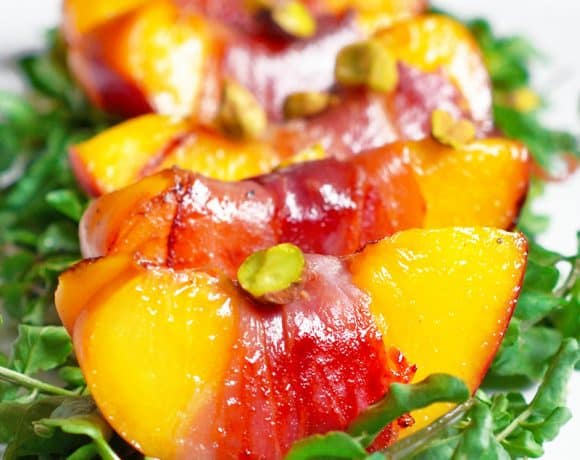 Closeup shot of watercress salad with prosciutto-wrapped peaches.
