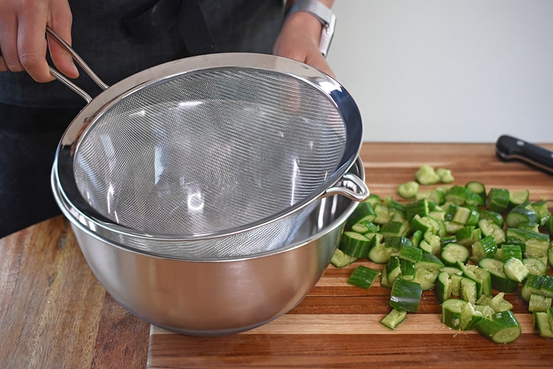 Placing a colander or fine meshed strainer inside a metal bowl.