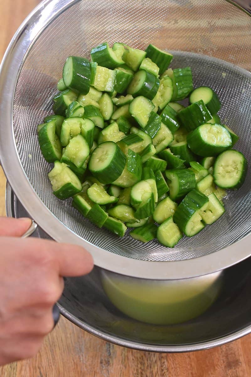 Take the cucumbers in the colander or fine mesh strainer out of the metal bowl.