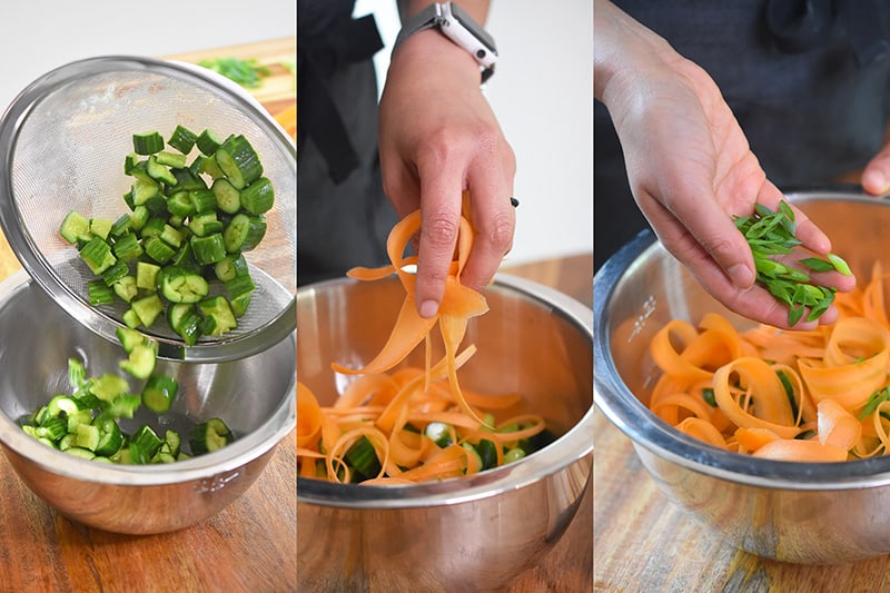 Pour the cucumbers, ribboned carrots, and sliced scallions into a metal bowl.