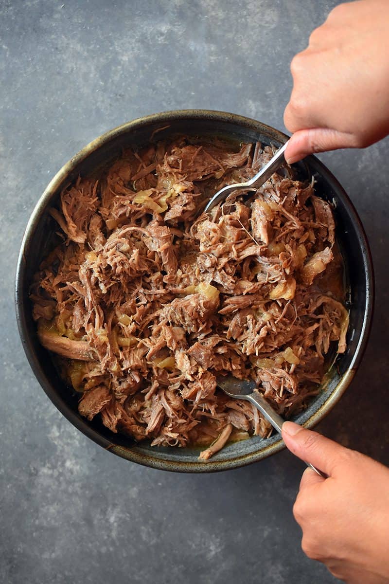 An overhead shot of Instant Pot Magic Pork in a large bowl being served with two forks.