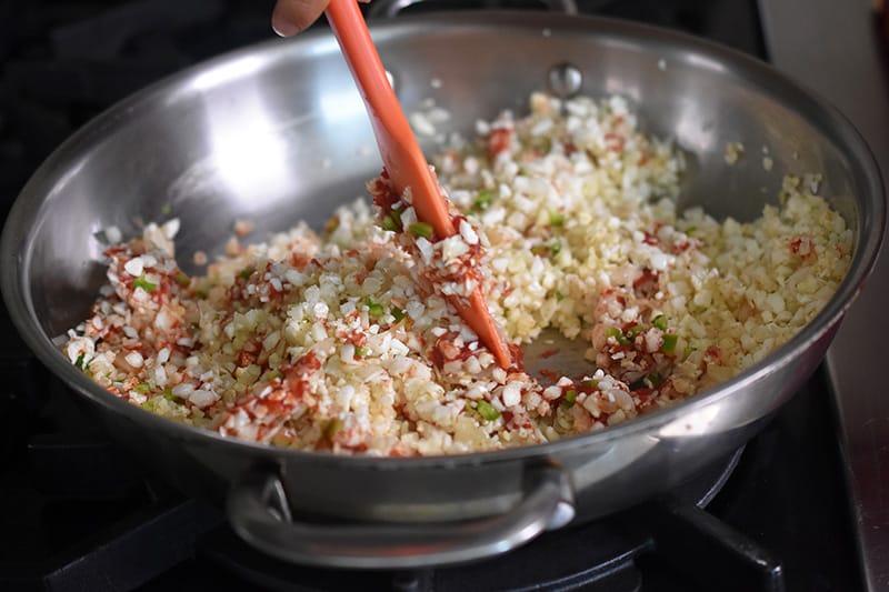 Stirring the paleo Mexican cauliflower rice in a skillet with a silicone spatula
