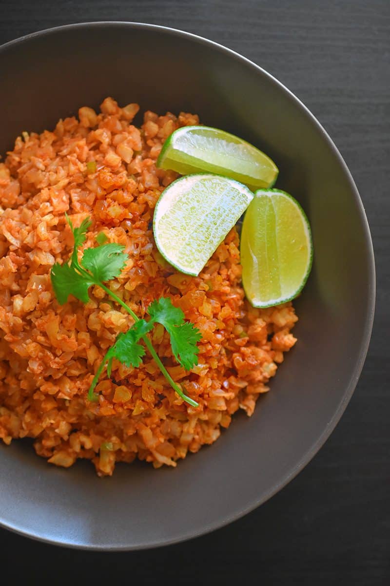 Overhead shot of Mexican Cauliflower Rice in a bowl with lime wedges