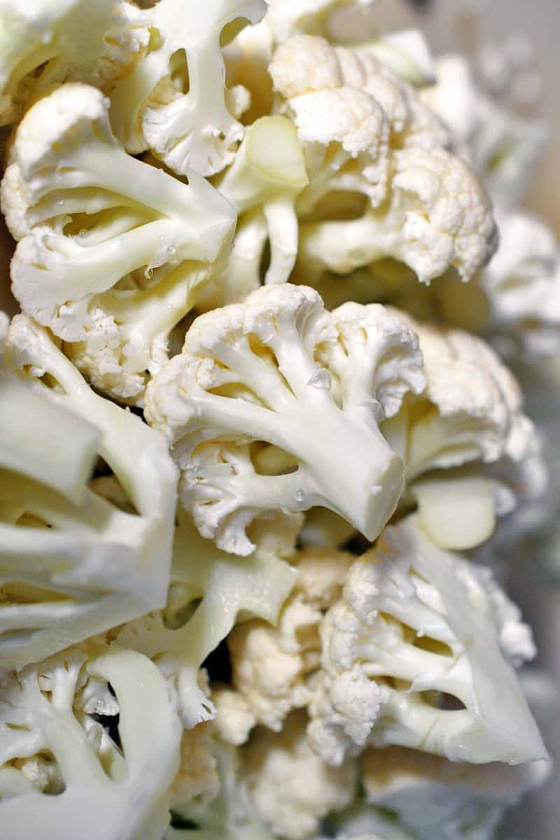 Overhead shot of raw cauliflower cut into uniform florets.