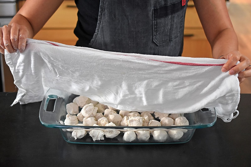Cover the dough balls with a damp kitchen cloth to keep them from drying out.
