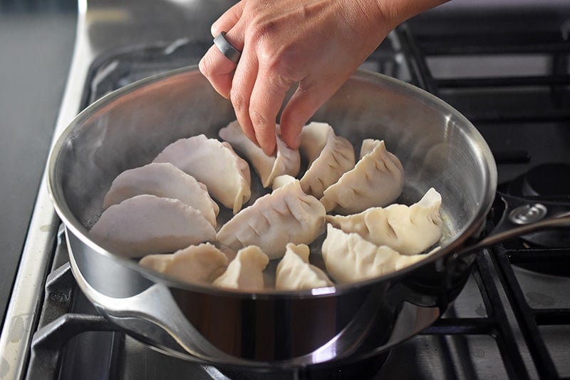 A 10-inch skillet is filled with a dozen Paleo Pot Stickers in a single layer.