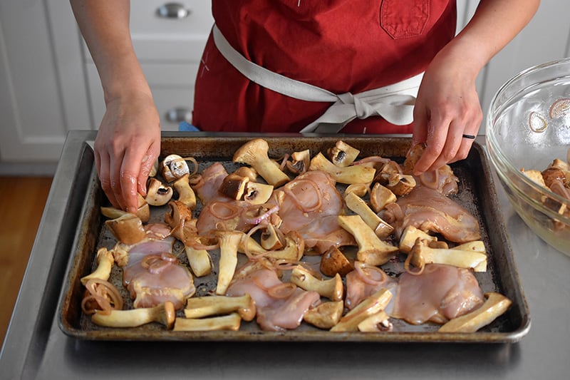 Arrange the mushrooms around the chicken thighs in a single layer.