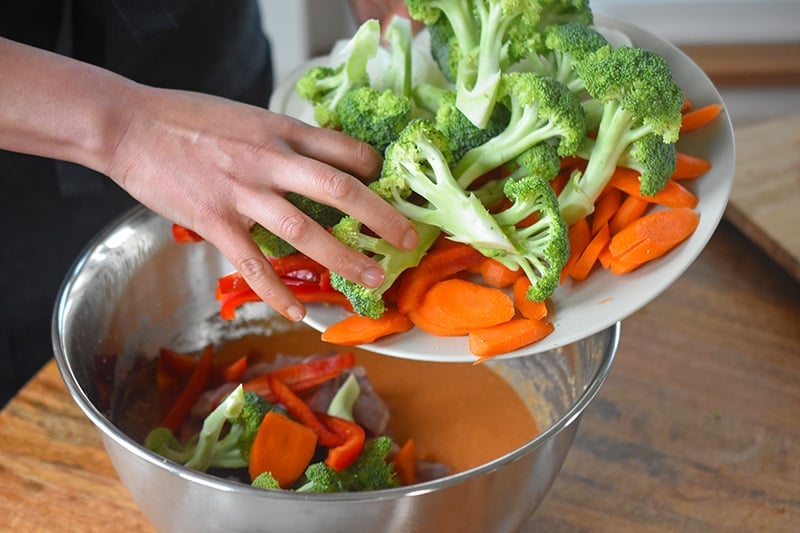 Cut up broccoli, carrots, and red bell peppers are added to the curry sauce.