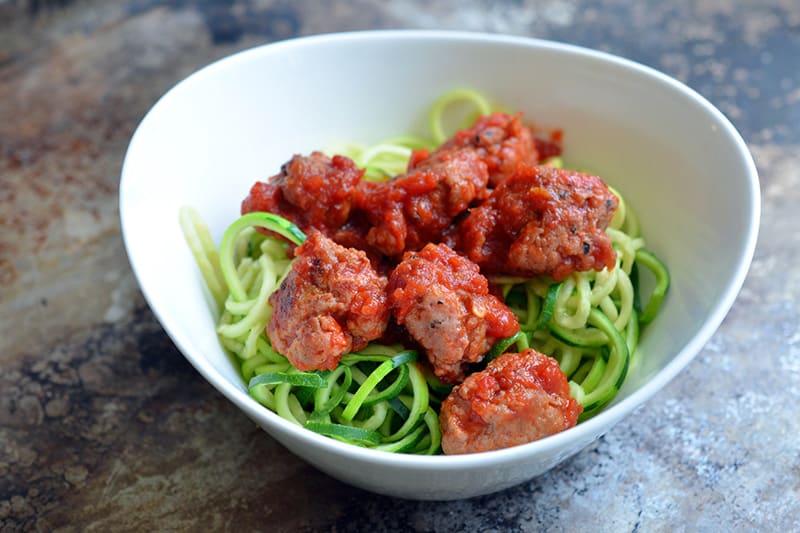 A closeup picture of Zoodles and Meatballs in a white bowl.