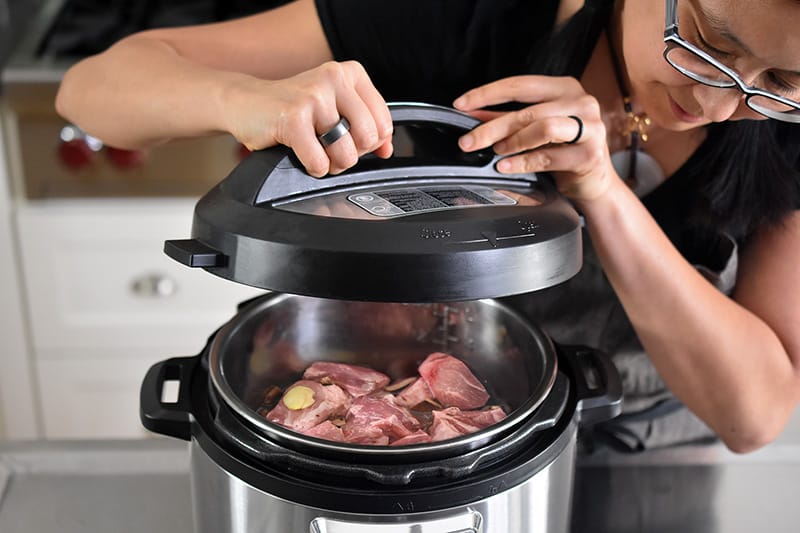 A person is placing the lid on top of the Instant Pot .