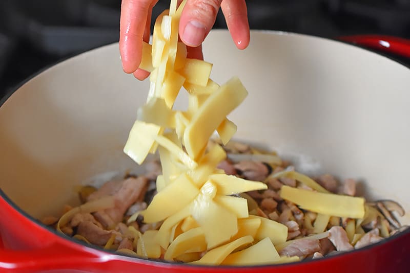Adding sliced bamboo shoots to the pork and vegetable mixture for Hot and Sour Soup