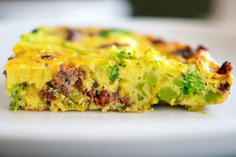A side shot of a slice of Easy Paleo Frittata on a white plate.