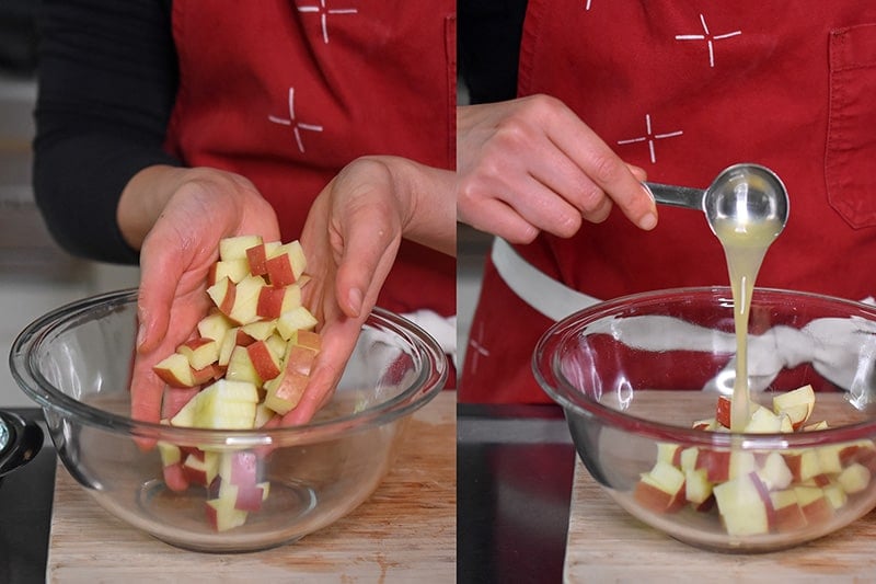 Tossing apple cubes with lemon juice in a glass bowl.