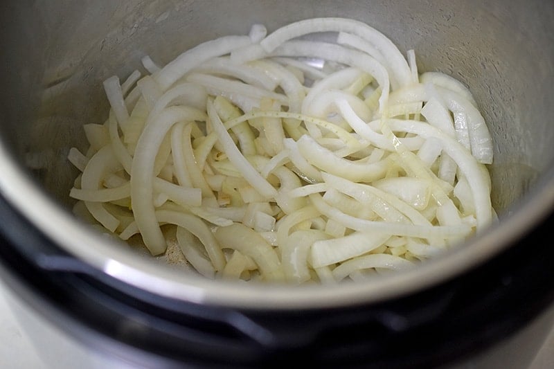 A closeup shot of the interior of an Instant Pot filled with sautéed sliced onions.
