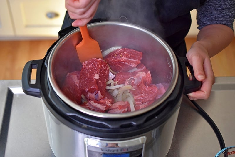 An overhead shot of someone stirring the contents of Instant Pot Chinese Beef Stew before pressure cooking it.