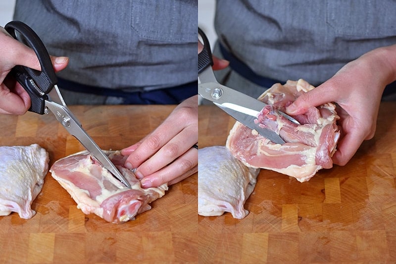 A person is using kitchen shears to cut out the bone from chicken thighs.
