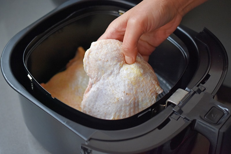 Arranging boneless, skin-on chicken thighs in a single layer in an air fryer basket