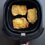 An overhead shot of three crispy pieces of Air Fryer Cracklin' Chicken in an air fryer basket.