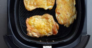 An overhead shot of three crispy pieces of Air Fryer Cracklin' Chicken in an air fryer basket.