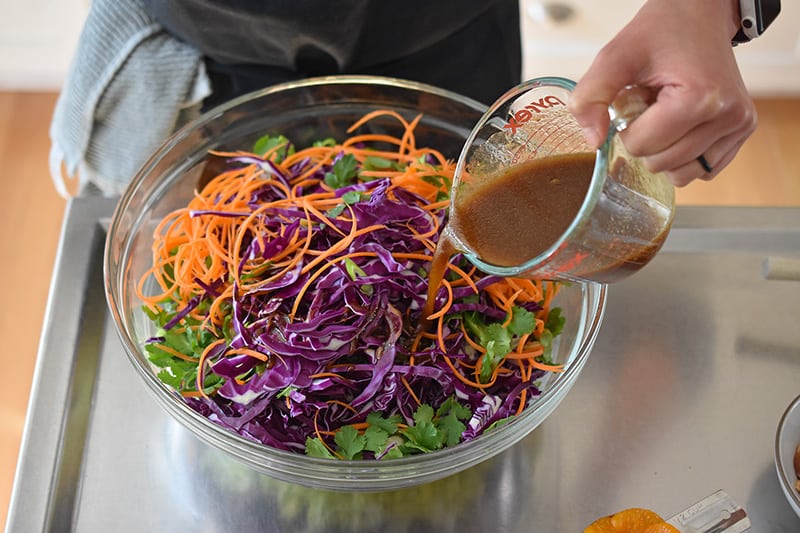 Pouring the paleo salad dressing over the Whole30-friendly Chinese Chicken Salad.