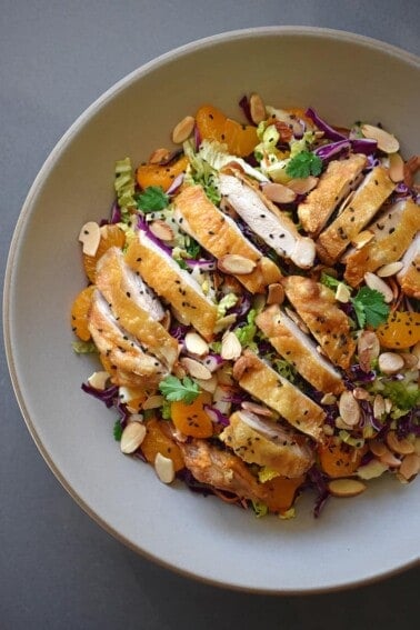 An overhead shot of Whole30-friendly Chinese Chicken Salad, a colorful blend of cabbage, carrots, mandarin oranges, herbs, and crispy Cracklin' Chicken.