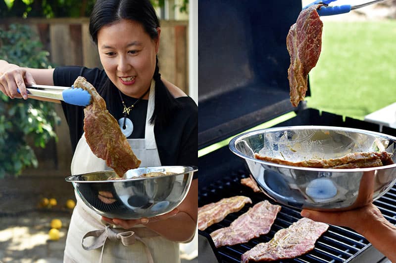 An Asian woman is grabbing marinated paleo kalbi with a pair of tongs and placing them on the grill.